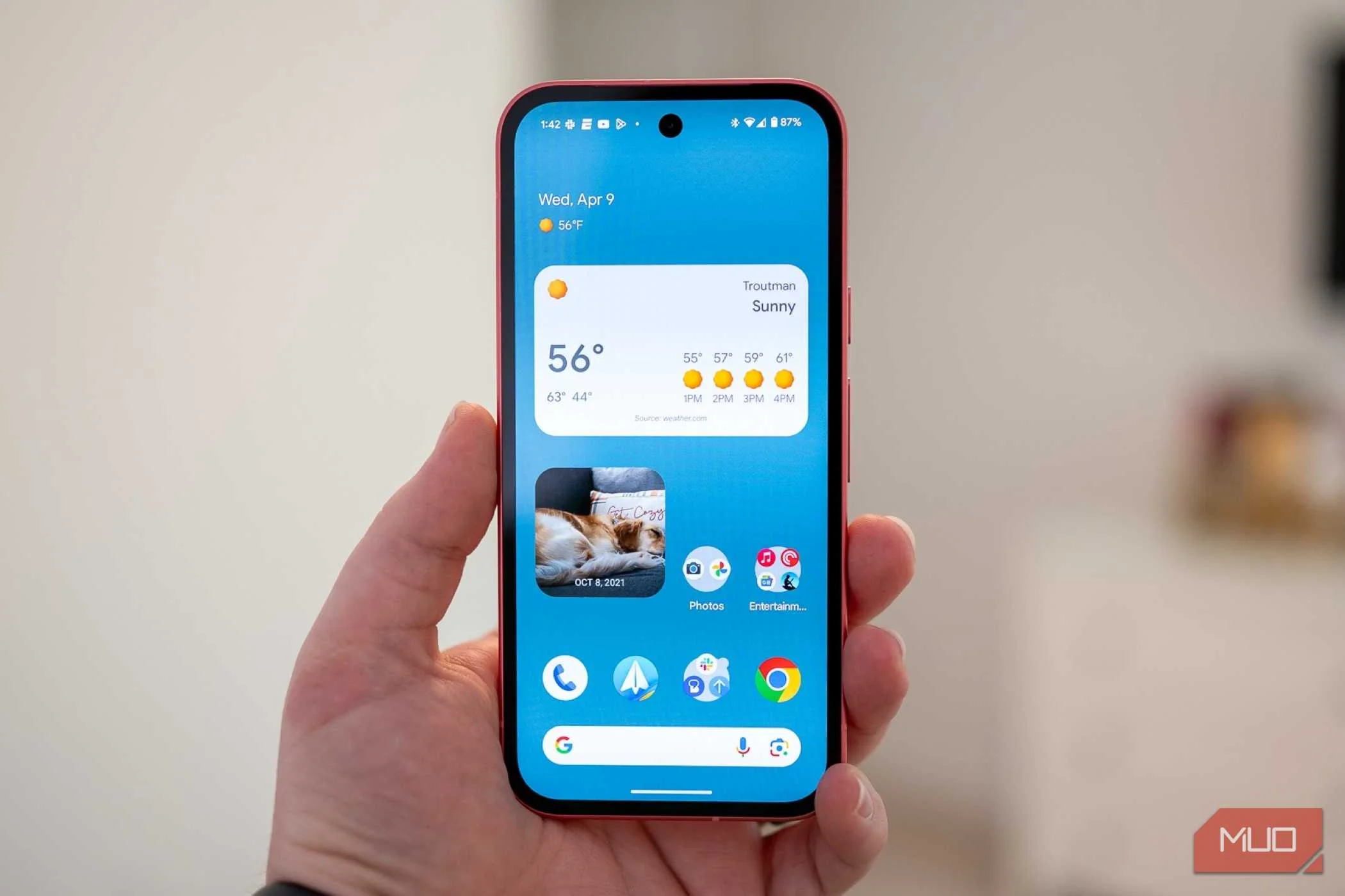 Person holding the Google Pixel 9a showing the home screen.